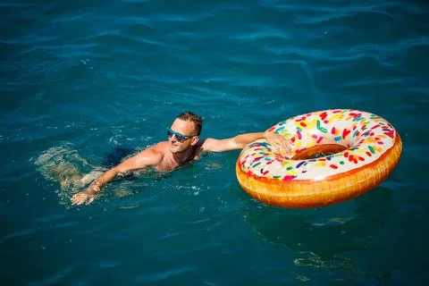 Young man on an inflatable ring in the sea resting and swimming on a sunny da 스톡 사진