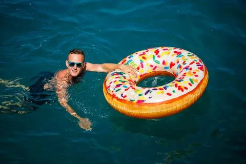 Young man on an inflatable ring in the sea resting and swimming on a sunny da 스톡 사진