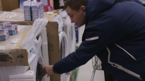 Young man is inspecting a washing machine at the shop Stock Footage 74434205