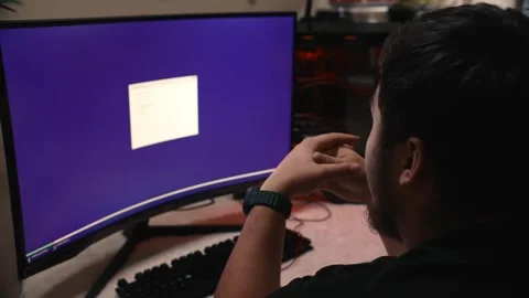 Young man installing operating system on computer with widescreen monitor Stock Footage 323438234