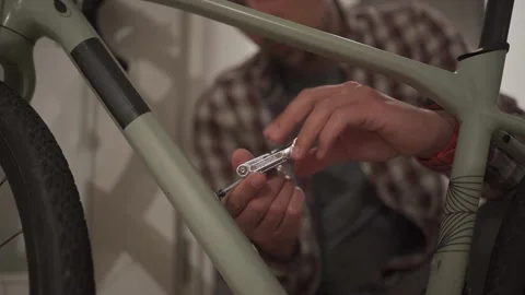 A young man installs a bicycle accessory at home in a studio apartment. A young Stock Footage 211455749