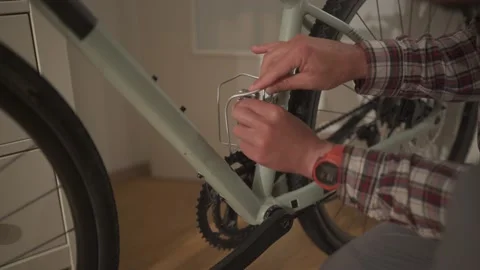 A young man installs a bicycle accessory at home in a studio apartment. A young Stock Footage 211457965