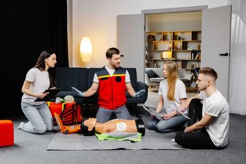 Young man instructor helping to make first aid heart compressions with dumm.. Stock Photos