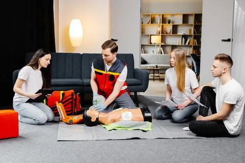 Young man instructor helping to make first aid heart compressions with dumm.. Stock Photos