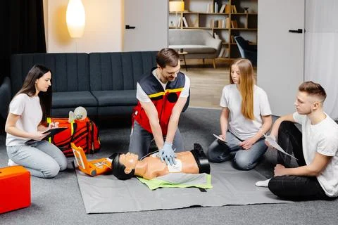 Young man instructor helping to make first aid heart compressions with dumm.. Stock Photos