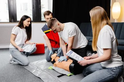 Young man instructor helping to make first aid heart compressions with dumm.. Stock Photos