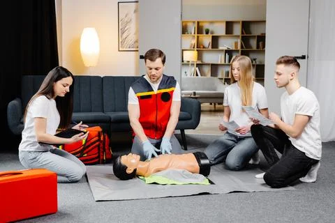 Young man instructor helping to make first aid heart compressions with dumm.. Stock Photos