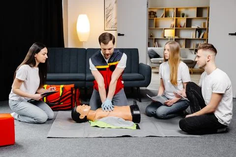 Young man instructor helping to make first aid heart compressions with dumm.. Stock Photos