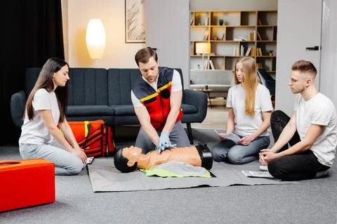 Young man instructor helping to make first aid heart compressions with dumm.. Stock Photos