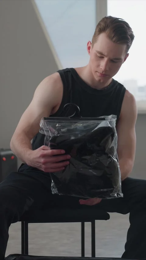 Young man interacting with suitcases and plastic bags while seated indoors near Vídeo Stock 344425609