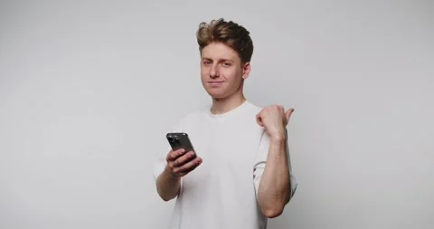 Young man interacts with smartphone in a minimalistic studio setting Stock Footage 316180850