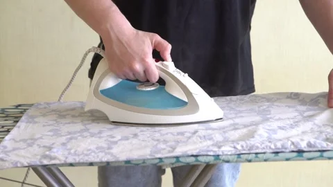 Young man ironing clothes on a board, homework Stock Footage 157365814