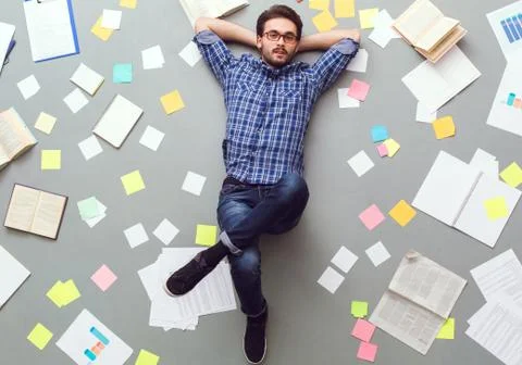 Young man isolated on grey background with papers and notes relaxed looking Stock Photos
