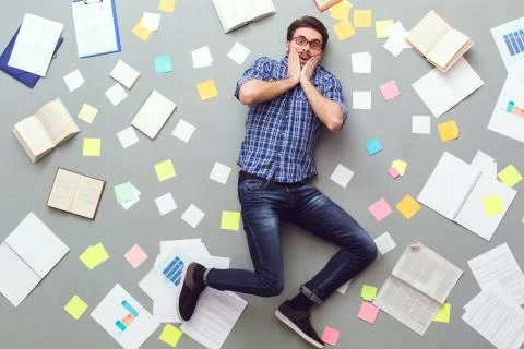 Young man isolated on grey background with papers and notes looking camera Stock Photos