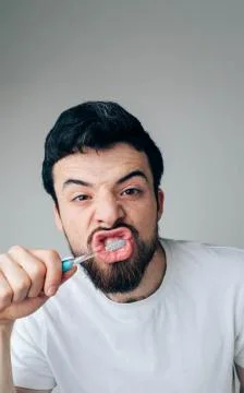 Young man isolated over background. Guy cleaning his teeth hard and concentrated 库存照片