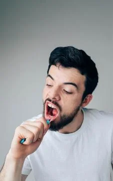 Young man isolated over background. Hardworking serious guy cleaning teeth with Stock Photos