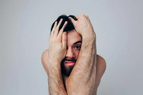 Young man isolated over background. Portrait of a worried guy covering face with 库存照片