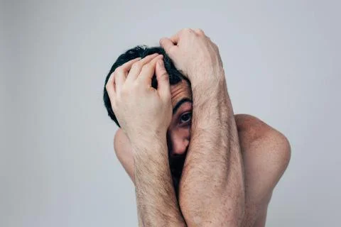 Young man isolated over background. Sick ill mad guy look straight through hands Stockfoto's