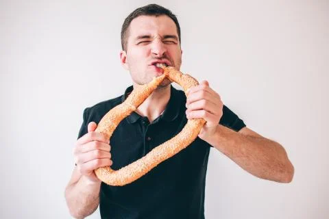 Young man isolated over background. Picture of guy holding big round bun and Stock Photos