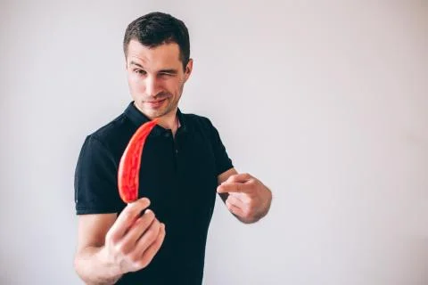 Young man isolated over background. Guy hold ripe hot pepper in hand and show it Stock Photos