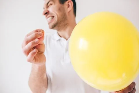 Young man isolated over white background. Guy pierce a balloon with needle Stock Photos