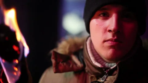 Young man in jacket and hat holding a torch andlooking somewhere Stock Footage 64701920