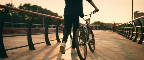 A young man in a jacket drives a bicycle on a sports field. Stock Footage 139845845