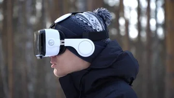 A young man in a jacket, in a hat, in glasses of virtual reality against the bac 스톡 동영상 85994442