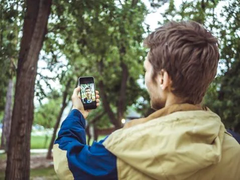 Young man in jacket making a selfie outdoors with his smartphone Foto stock