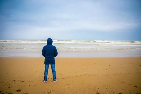 Young man in jacket on sandy beach of Rimini in winter, Italy Stock Photos