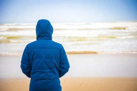 Young man in jacket on sandy beach of Rimini in winter, Italy Stock Photos