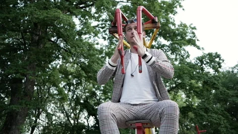 Young man in jacket works out on a street simulator in an outdoor Park Stock Footage 138219197