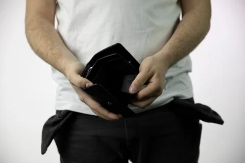 Young man in jeans with empty pockets shows his empty wallet Stock Photos