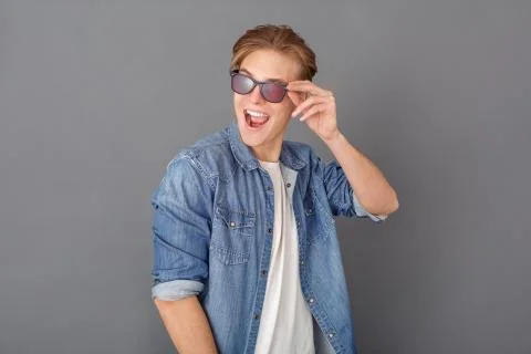 Young man in jeans jacket studio isolated on grey looking aside happy Foto stock