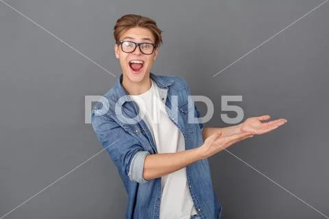 Young Man In Jeans Jacket Studio Isolated On Grey Showing Copyspace Cheerful