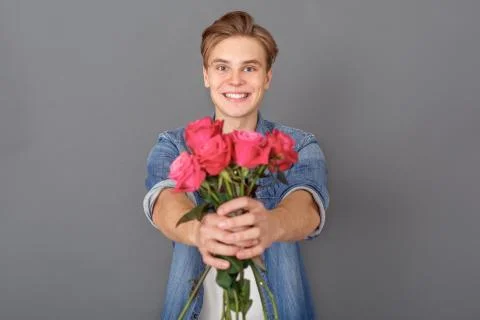 Young man in jeans jacket studio isolated on grey celebration concept with Stock Photos