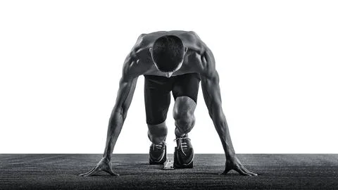 Young man, jogger, sprinter standing on start line, ready and focused, looking Stock Photos