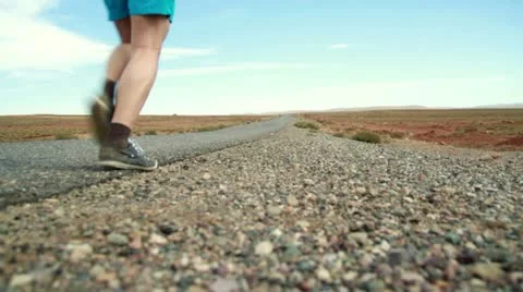 Young man jogging and drinking water on desert road, dolly shot, slow motion Vídeos de archivo 10842377