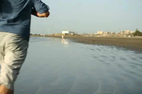 Young man jogging on the beach, slow motion NTSC Stock Footage 10894416