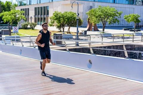 Young man jogging on a bridge over a city canal Stock Photos