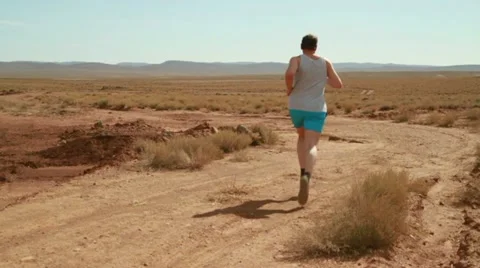 Young man jogging on desert track, slow motion Vídeos de archivo 10842384