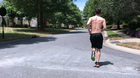 Young man jogging down a street Stock Footage 65051096