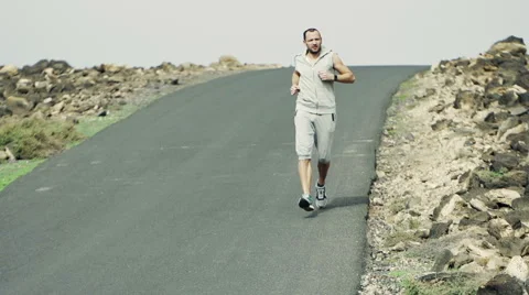 Young man jogging down through road and checking time, slow motion  HD Stock Footage 46148967