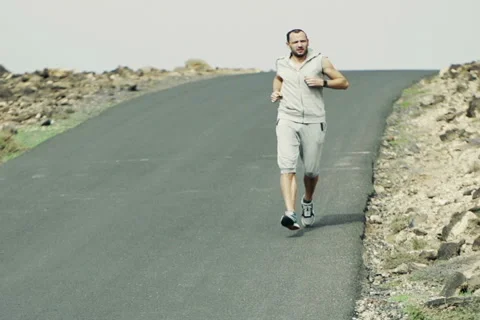 Young man jogging down through road and checking time, slow motion  NTSC Stock Footage 46149113