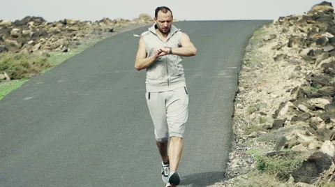 Young man jogging down through road and checking time HD Stock Footage 47453256