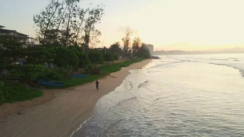 Young man jogging on the empty beach sundown drone footage Stock Footage 84927505