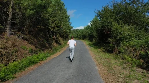 Young man jogging on the road in the forest Stock Footage 114021343
