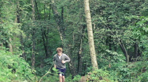 Young man jogging uphill through forest Stock Footage 41094538