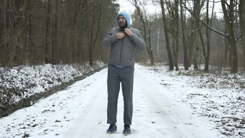 Young man jogging in winter forest, checking time on phone Stock Footage 88676131