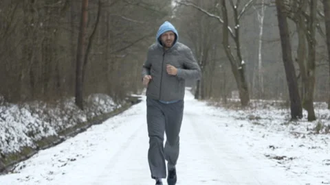 Young man jogging in winter forest, checking time on phone Stock Footage 95139930